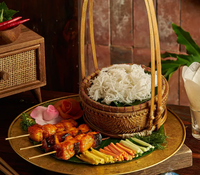 Grilled fish on a rack with rice noodles and herbs