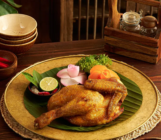 Roast chicken on a banana leaf with herbs and lime