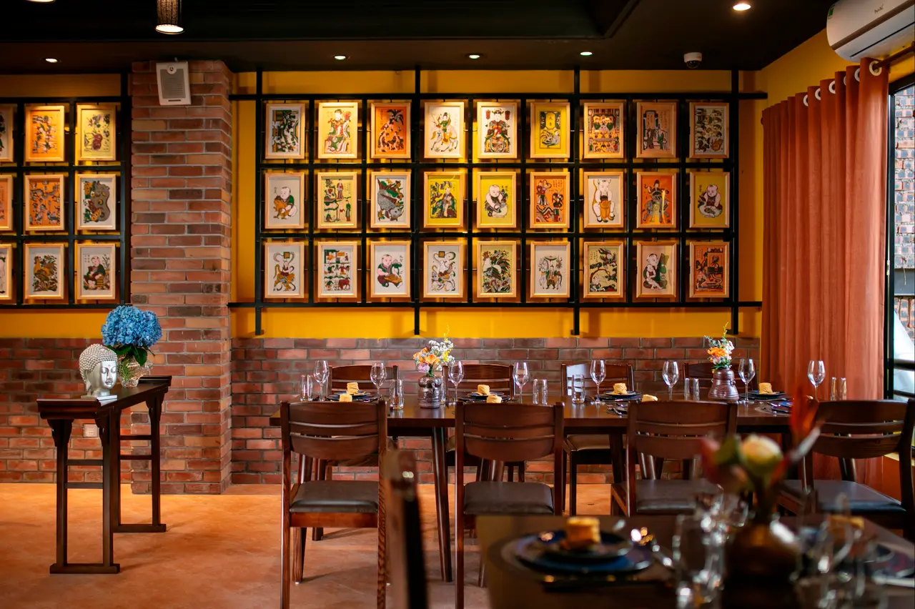 Wall of framed folk prints above set tables