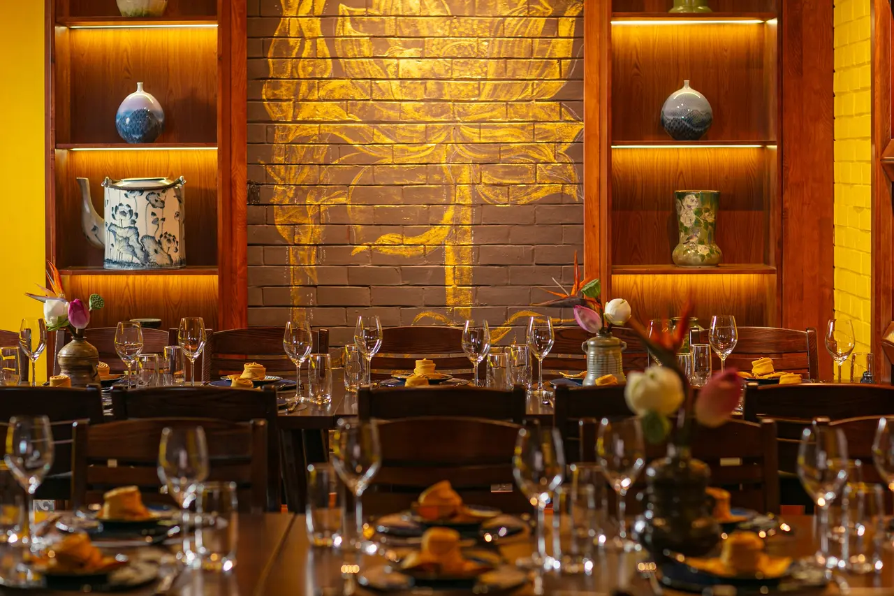 Golden lotus mural on brick between lit wooden shelves