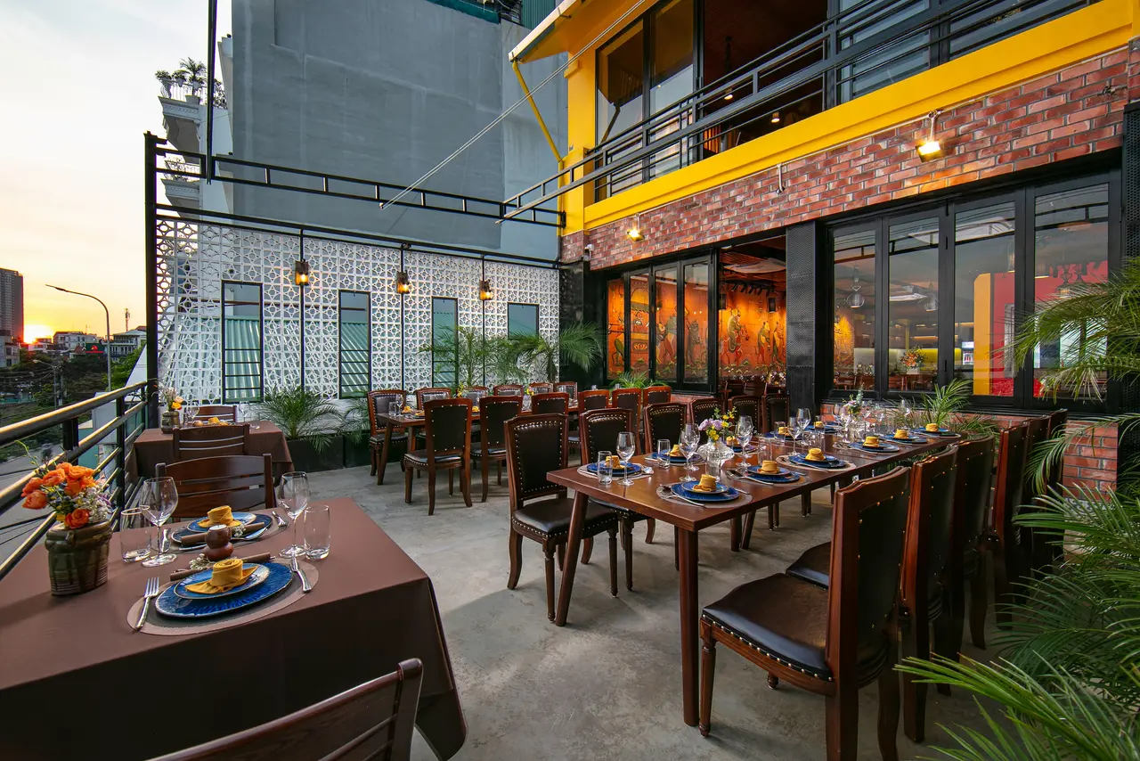 Open-air terrace at sunset with a white lattice wall and set tables